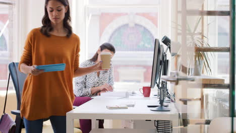 mixed race team of young business people working in open plan office desk rows of computers in shared workspace bright natural light