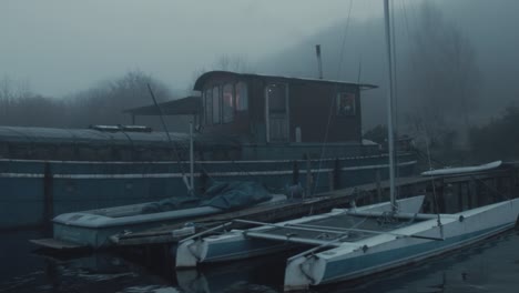 barge houseboat moored along shoreline among dense atmospheric fog