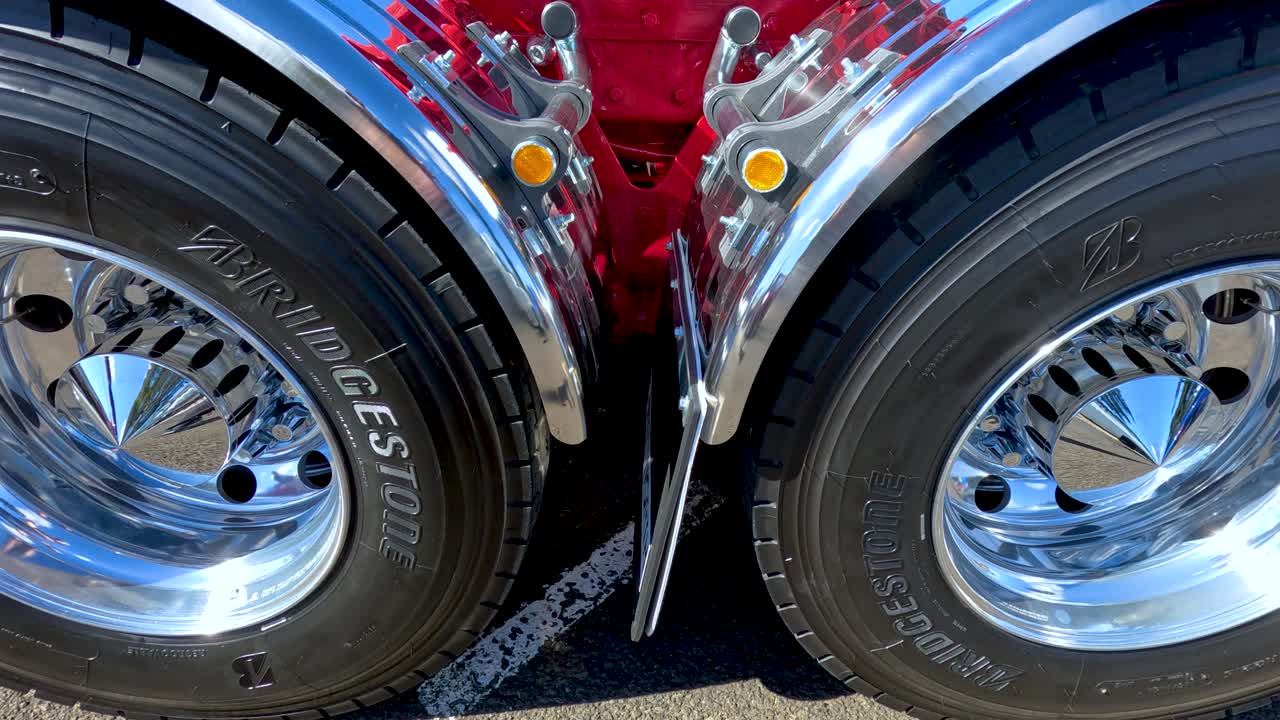 Smooth close-up pan of polished chrome truck wheels reflecting sunlight, highlighting shine and detail