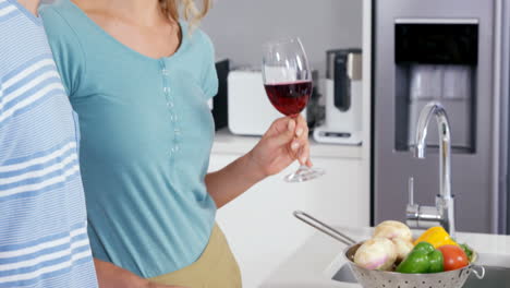 Cute-couple-preparing-the-meal-while-drinking-red-wine