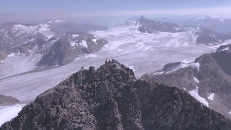 mountaineer approaching summit of a massive peak surrounded by mountains and glaciers