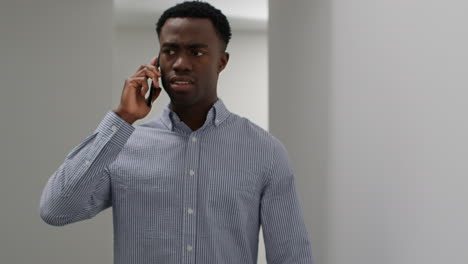 young businessman in office talking on mobile phone reacting to bad news looking unhappy and depressed