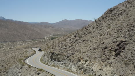 aerial shot of utility truck on winding mountain road in the california desert