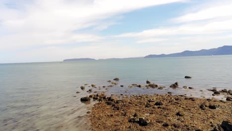 FPV-drone-flying-rocky-craggy-Welsh-coastline-on-Menai-Strait-seafront