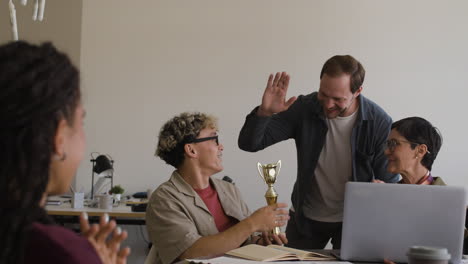 colleagues celebrate an award and high-five in the office