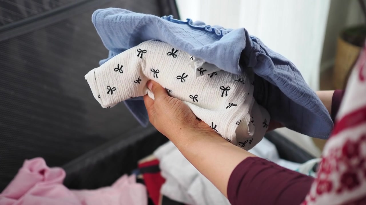 Person Packing Baby Clothes into a Suitcase