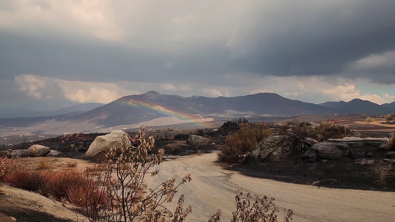 fairview fire secuelas de colinas quemadas, día lluvioso con pesadas nubes oscuras y arco iris, tiro panorámico