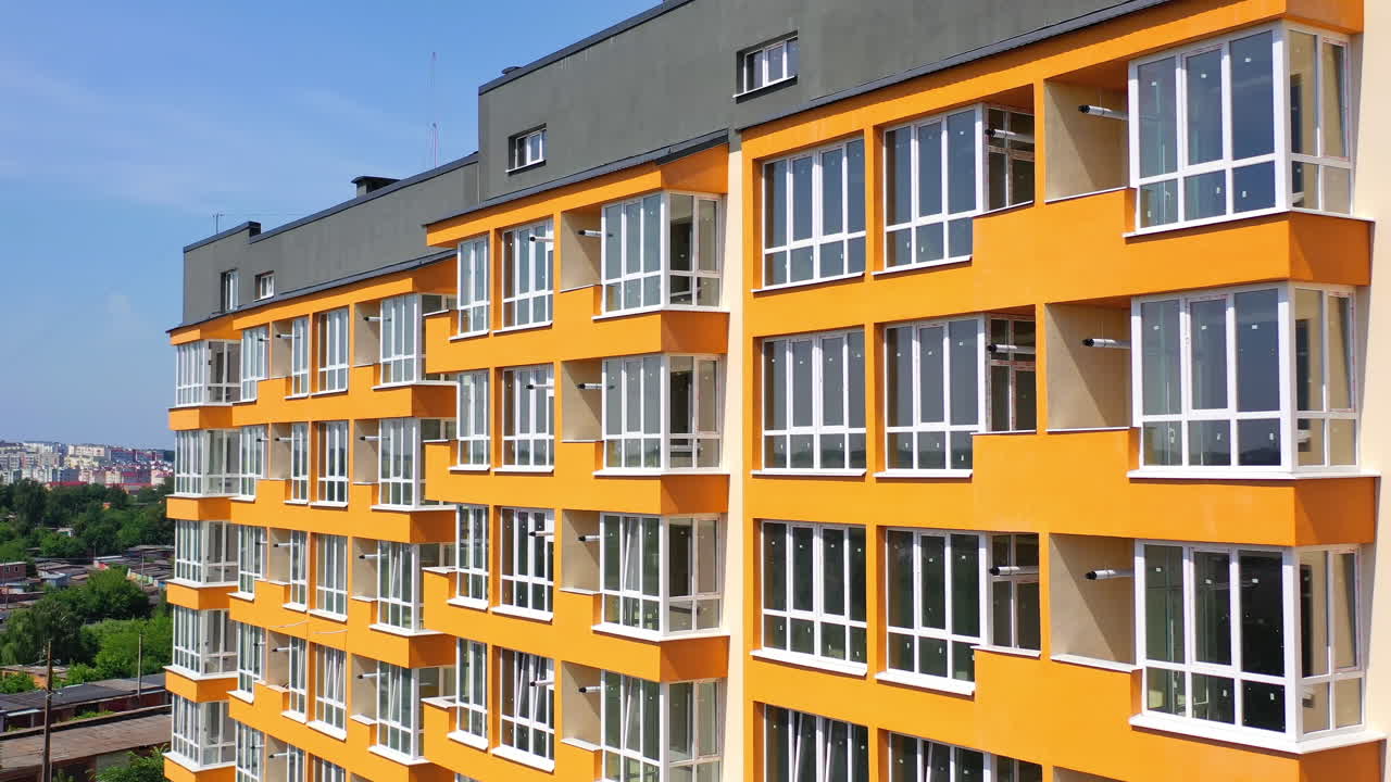 New multi storey in the city. Modern design of apartment building with orange walls with large balconies. Facade of luxury house for city residents.
