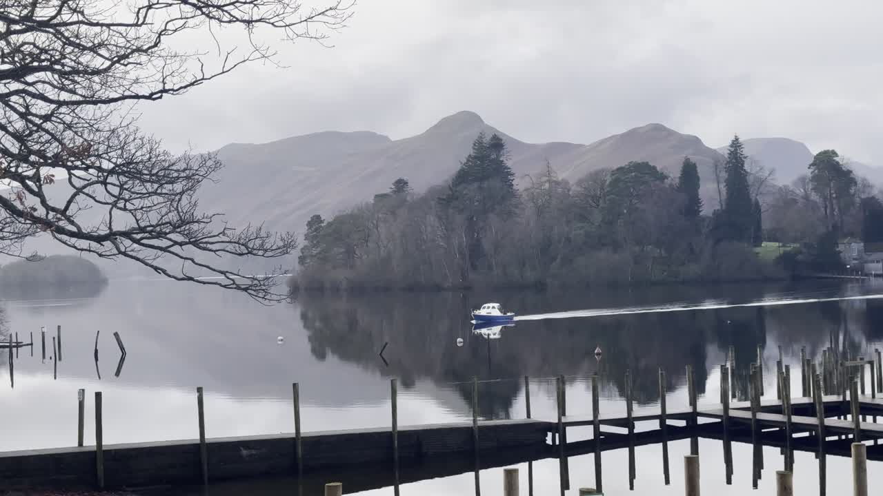 Boat on a lake on a grey moody day on Derwentwater overlooking Derwent Island and Catbells in the background - Keswick, Lake District