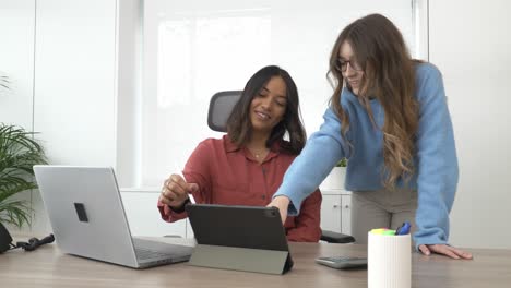 businesswomen collaborating on tablet in modern office