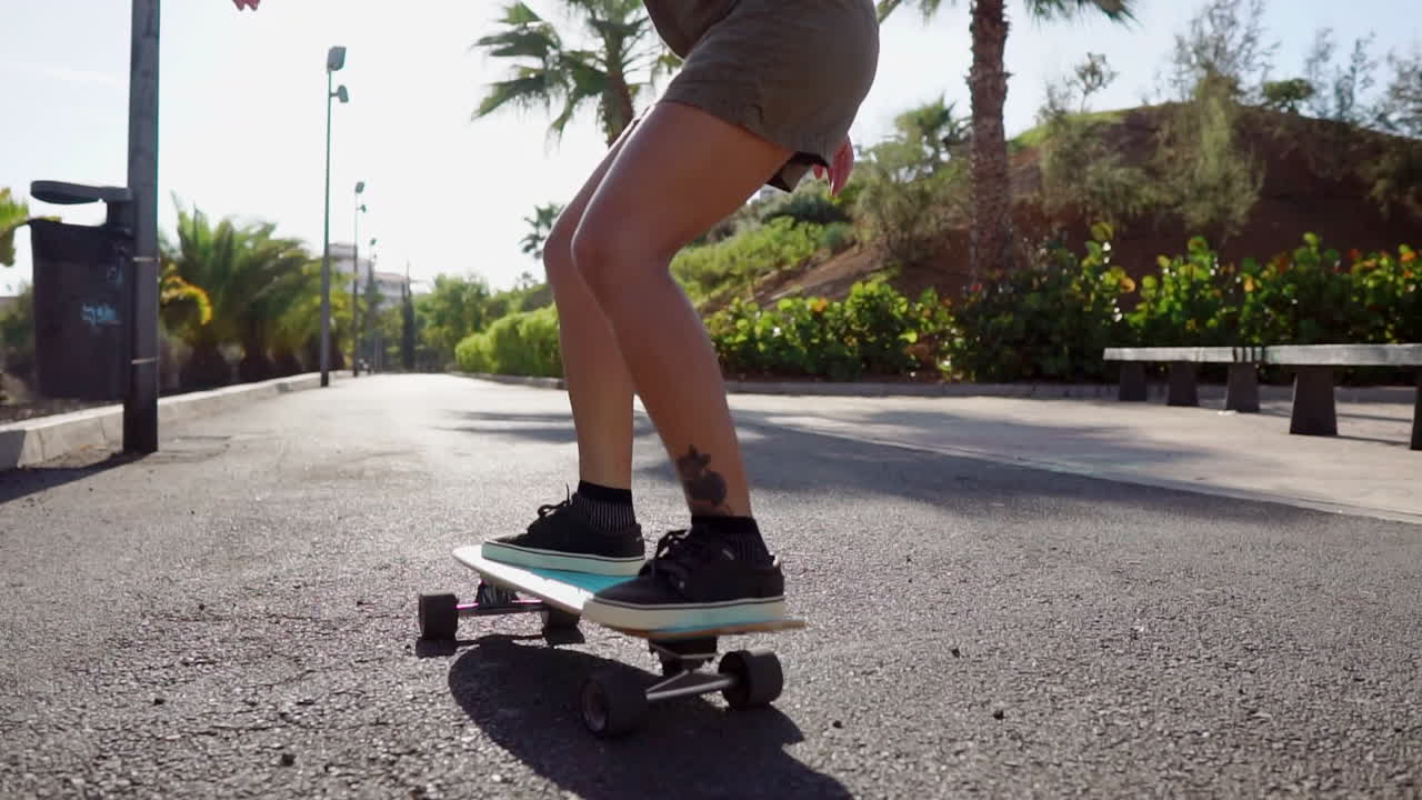 Against the picturesque backdrop of palm trees and the beach, slow motion highlights a young girl's serene longboard ride on the road
