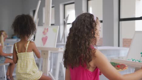 Video of back of diverse girls painting during art lessons at school