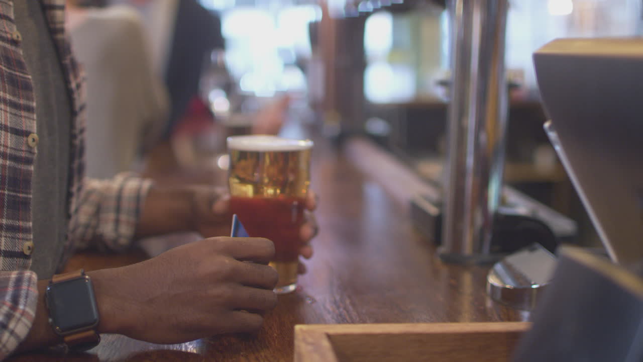 primer plano de un cliente masculino en un bar haciendo pago sin contacto para bebidas en una pandemia de salud