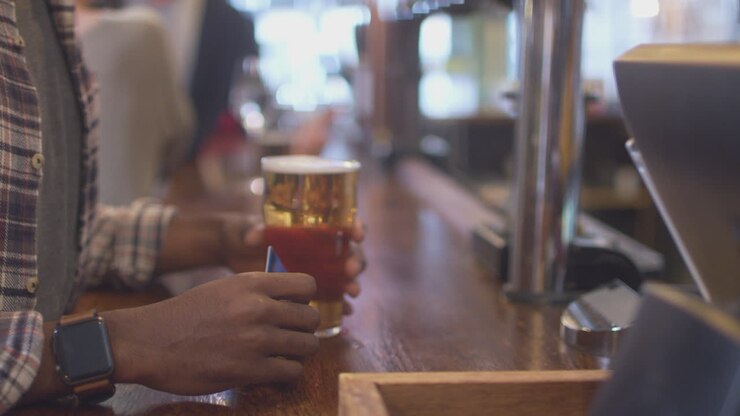 primo piano di un cliente maschio in un bar che paga senza contatto per le bevande in una pandemia sanitaria