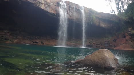 joven saltando en la cascada natural que cae desde la cima de la montaña en el video matutino tomado en la cascada krangsuri meghalaya india