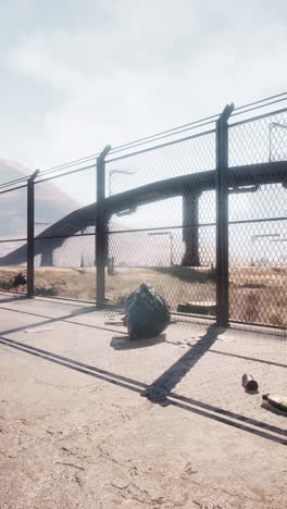 a rusty metal fence and a pipe bridge in a desert