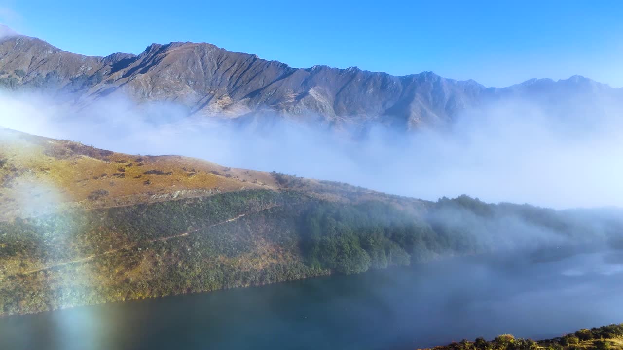A serene view of Moke Lake with mist rolling over the landscape, captured in vibrant daylight