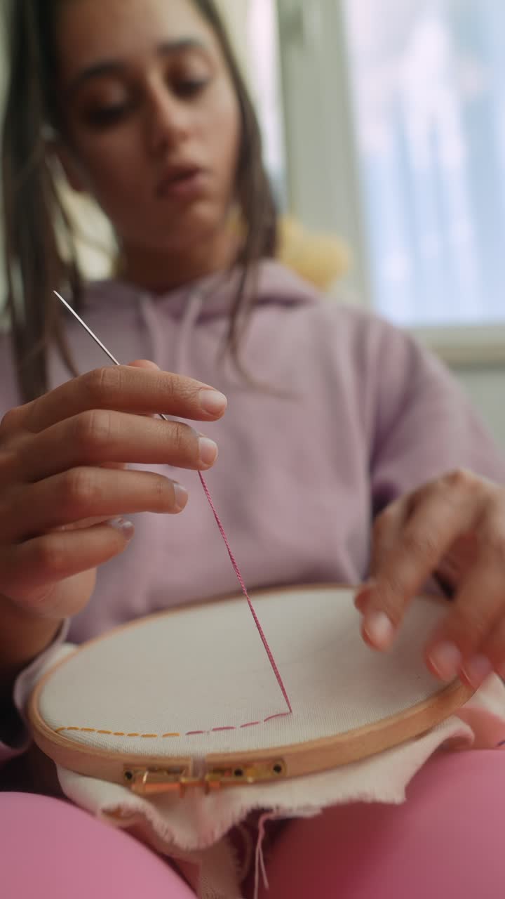 Young Woman's Hands Embroidering with Pink Thread on Fabric