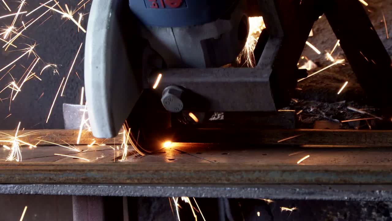 노동자는 금속 파이프를 밀러로 잘라내고, 많은 불꽃을 피운다.