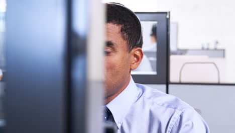 Mixed-race-man-working-in-a-call-centre-using-phone-headset