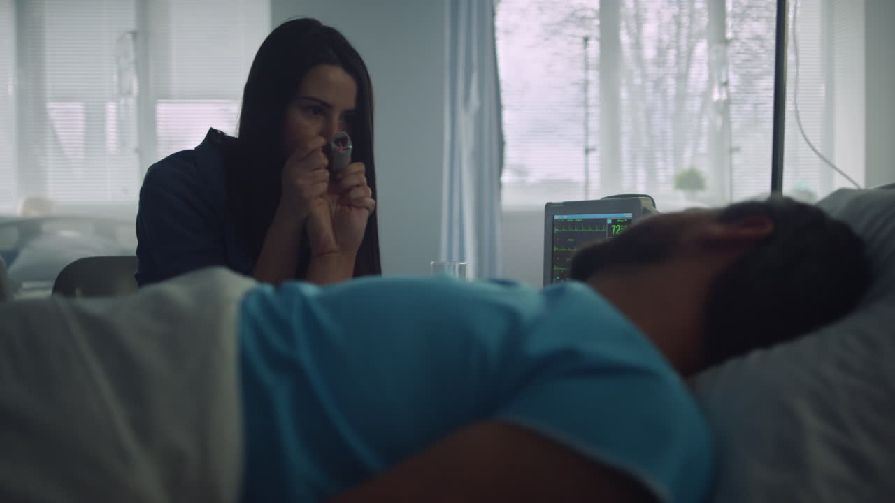 mujer de apoyo en la sala del hospital sosteniendo la mano del paciente inconsciente después de la cirugía.