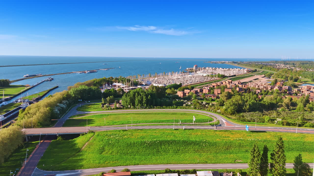 Flight over the green waterscape of lake Merkemeer. Approaching a large yacht club at backdrop.