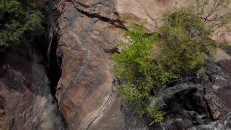 Mesmerizing-view-of-spectacular-steep-waterfall,-amidst-brown-rocky-mountain-forming-a-pond