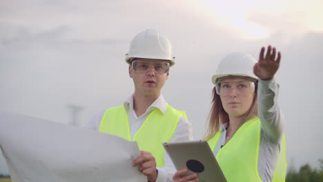 ingeniería trabajando en la torre de alta tensión comprobar la información en la computadora tablet dos empleados hombre y mujer
