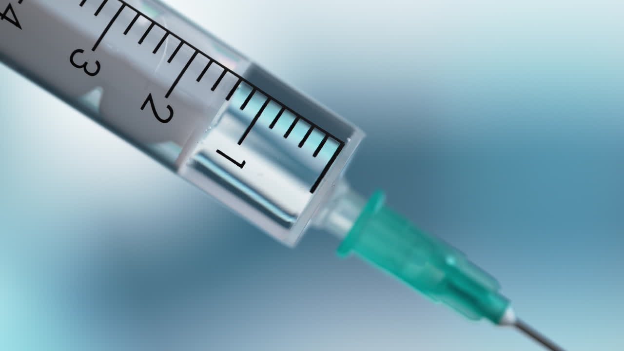 jeringa médica con una aguja en macro sobre un fondo azul borroso, dando inyección o vacuna en un hospital