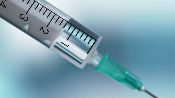 jeringa médica con una aguja en macro sobre un fondo azul borroso, dando inyección o vacuna en un hospital