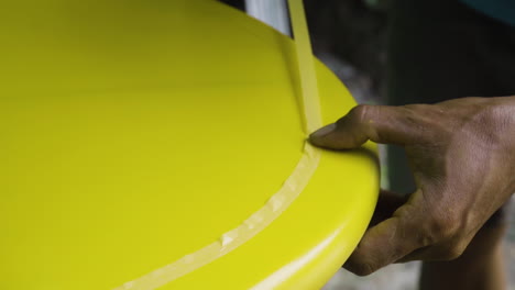 surfboard shaper puts painters tape on surfboard before painting