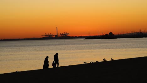 two people walking along beach at sunset