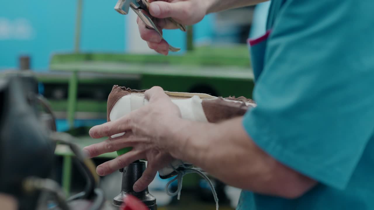 Worker cutting nails and hammering shoes for better molding in a factory