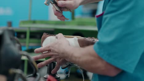 trabajador cortando clavos y martillando zapatos para un mejor moldeo en una fábrica