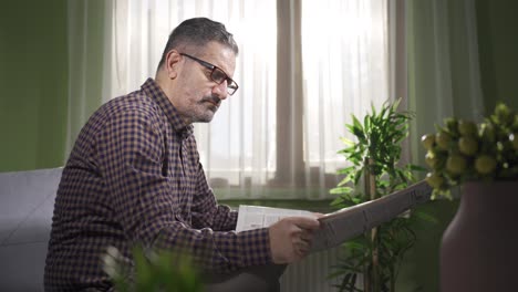 hombre de mediana edad con gafas leyendo el periódico en casa, disfrutando de su tiempo libre.