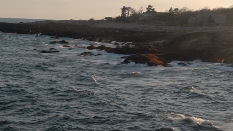 Stunning-Waves-Crashing-On-The-Rocky-Coast-During-Sunset-In-Gloucester,-Massachusetts---low-aerial,-slow-motion