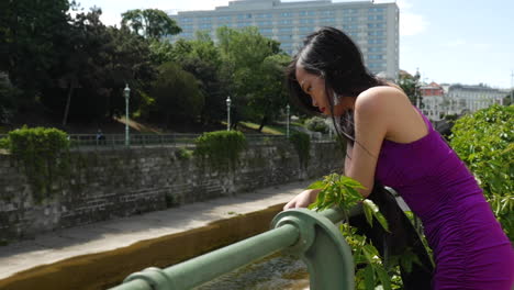 mujer asiática de pie en el puente mirando hacia abajo a cámara lenta, stadtpark viena