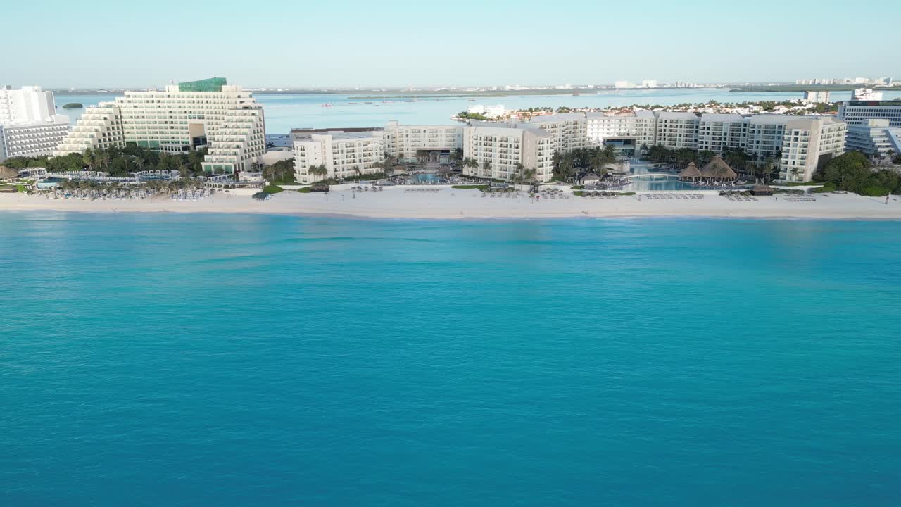 A luxury resort on a cancun beach with clear blue ocean waves, aerial view, playa delfines