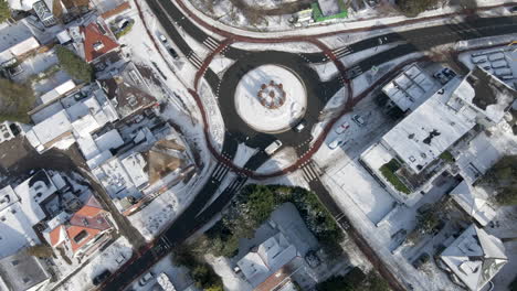 aerial of traffic driving around roundabout in winter