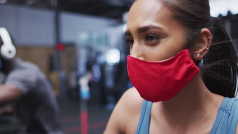 Mujer-De-Raza-Mixta-Con-Mascarilla-Haciendo-Ejercicio-En-El-Gimnasio