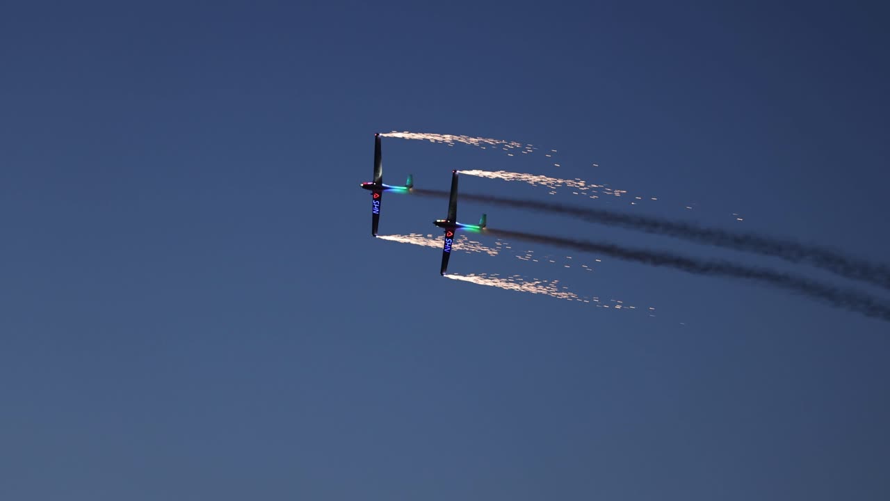 aeronaves pirotécnicas en tándem que lanzan fuegos artificiales mientras vuelan al unísono por la noche