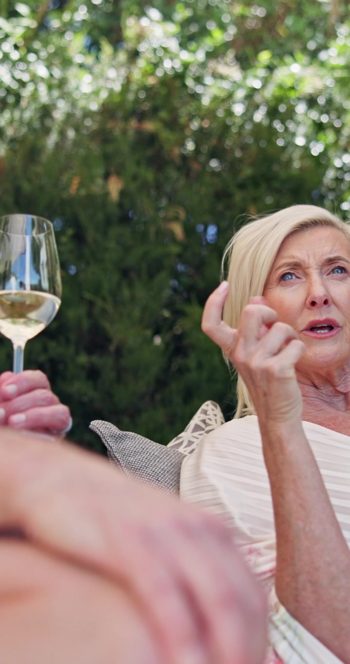 Mature Woman Talking and Drinking Wine Outdoors