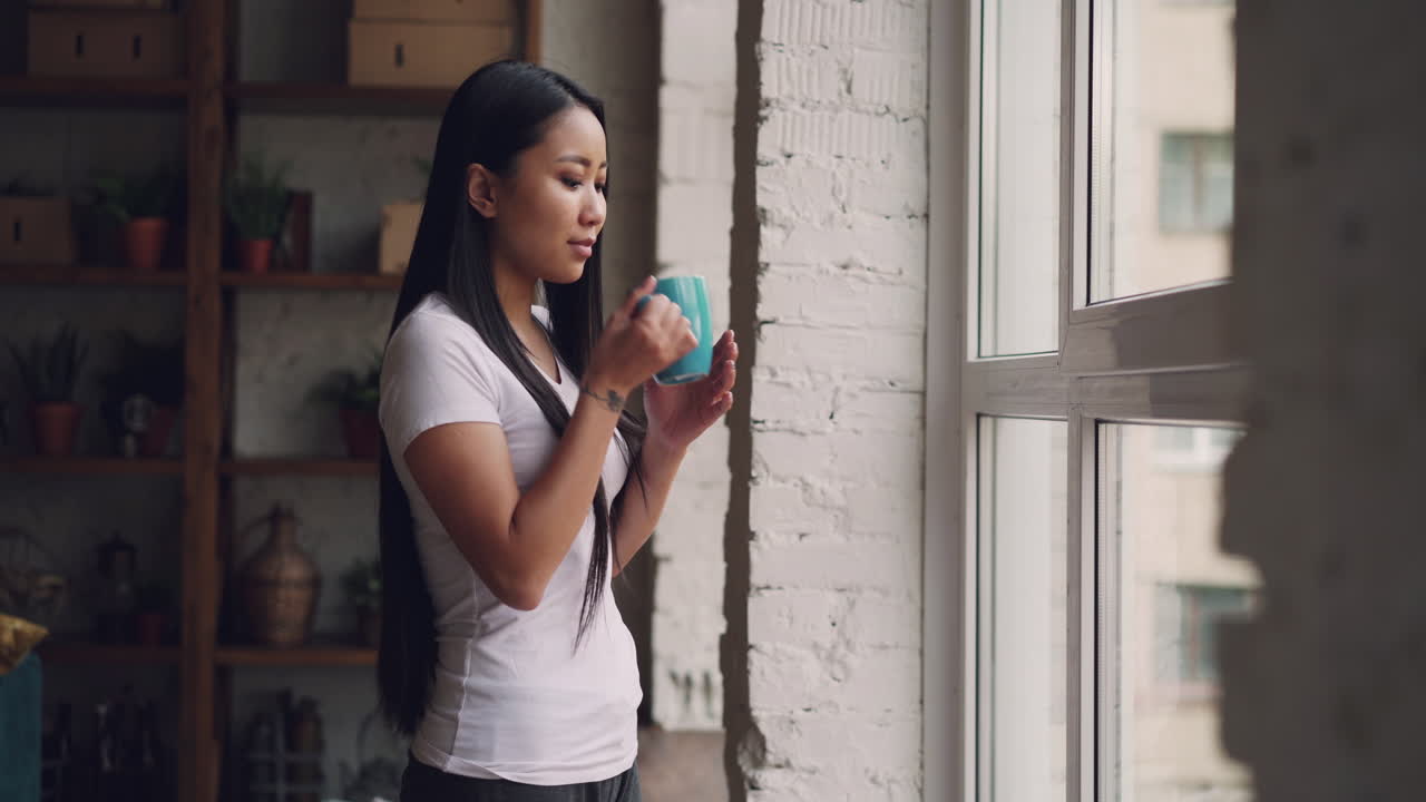 Woman drinking coffee by the window