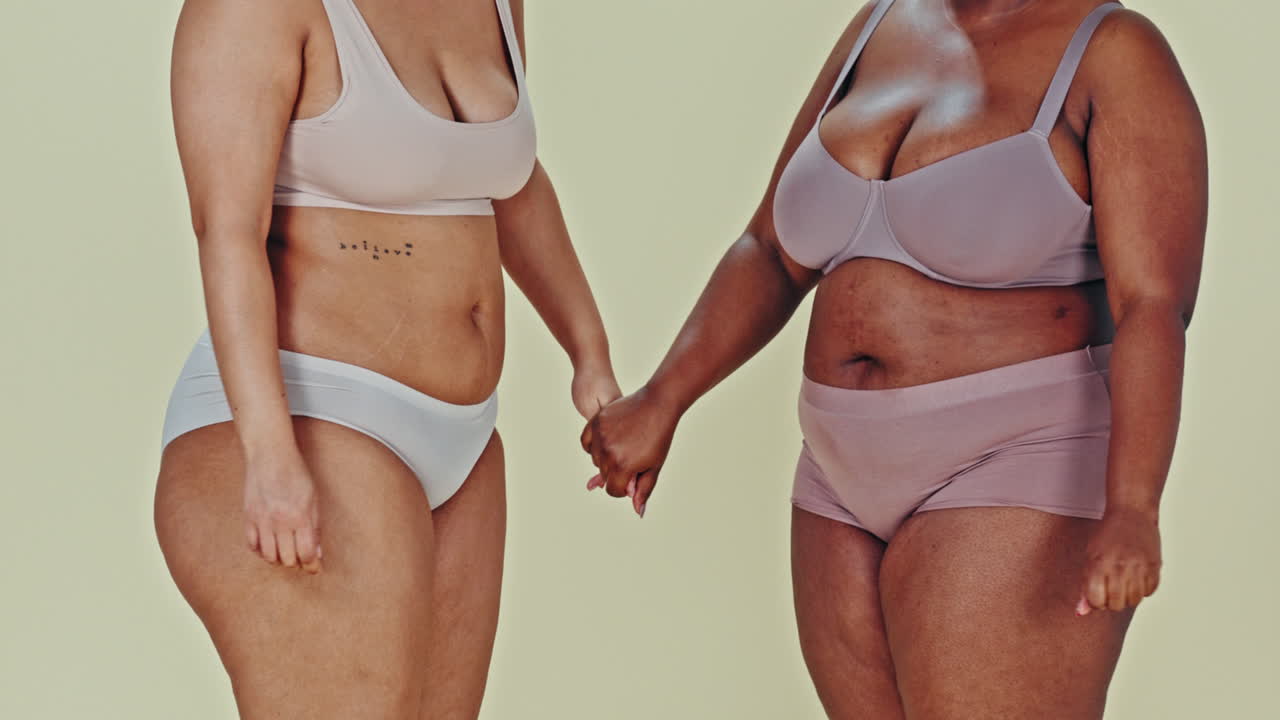 Two women holding hands in underwear representing body positivity