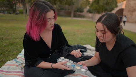 two women sharing makeup in park