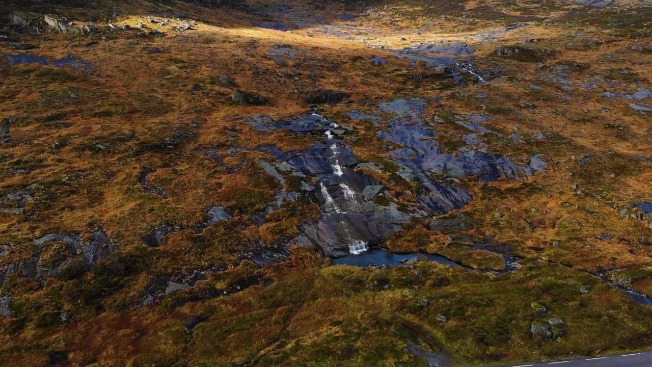 Drönare flyger mot ett vattenfall i de norska bergen på Lofoten