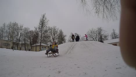 lady child slide down icy hill on toboggan in winter vacations-1