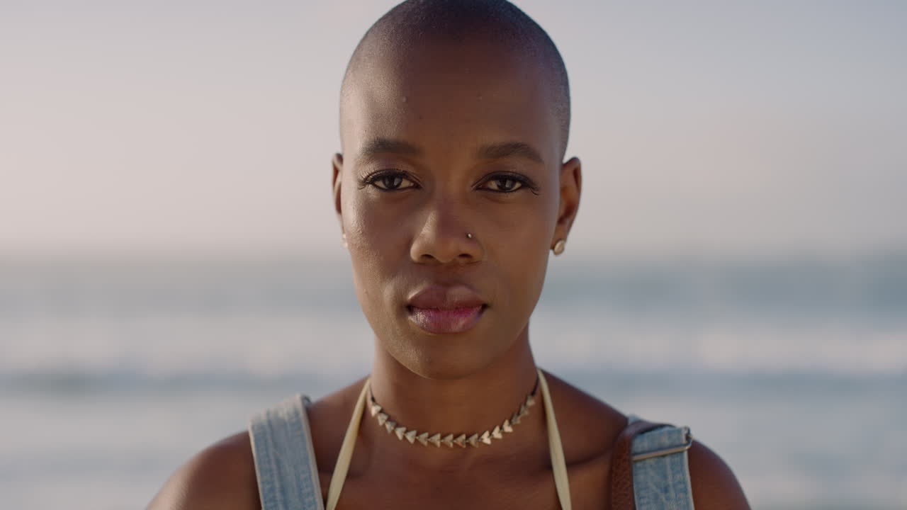 portrait of beautiful young african american woman looking calm pensive enjoying warm sunny seaside beach slow motion