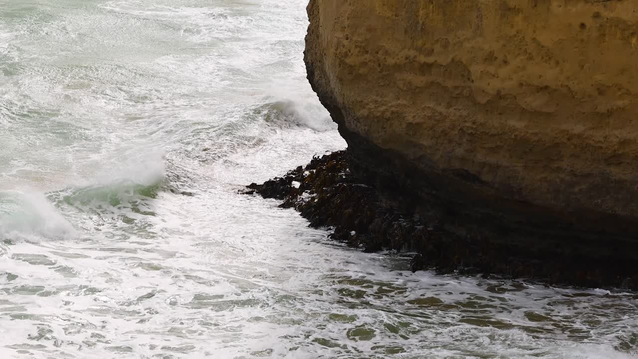 Dynamic ocean waves crash against rugged cliffs at Port Campbell, Australia, under natural daylight, showcasing the power of nature
