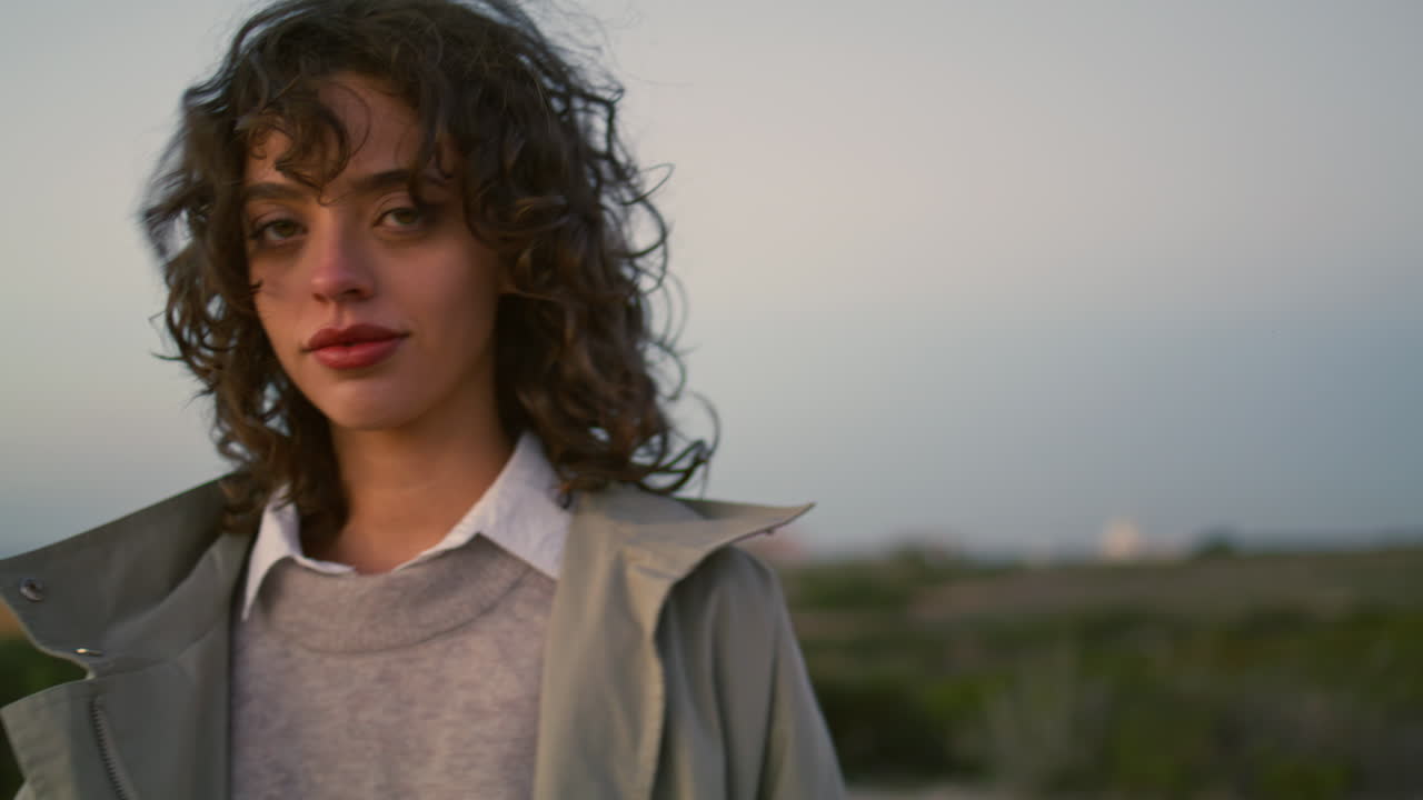Primo piano di ragazza pensierosa che cammina nel paesaggio serale. Sguardo rilassato di una bella millennial.